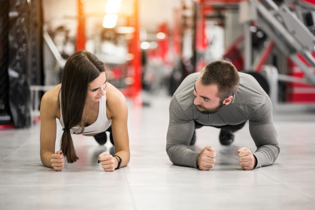 A man and woman perform the plank exercise designed for all muscle groups